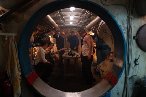 Several men stand around a table in a submarine