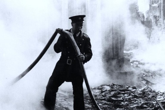 A fireman pulls his hose through the smouldering ruins of a bombed out church in London in the Blitz.